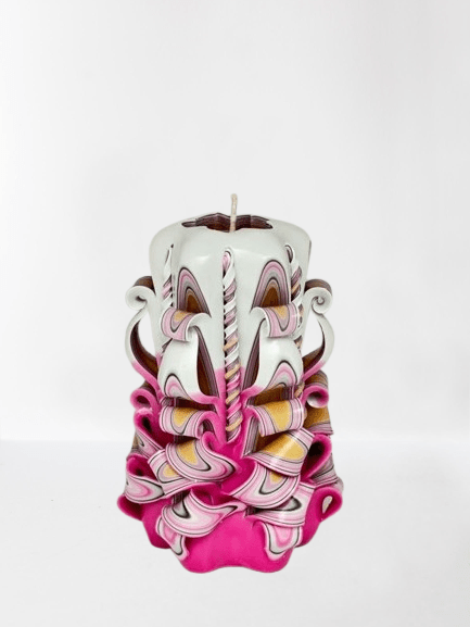 Eine kunstvoll handgeschnitzte Design Kerze in zartem Rosa, 14 cm hoch, mit filigranen Verzierungen und elegantem Muster.